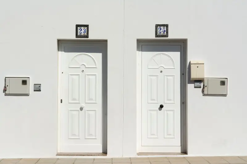 Two identical white apartment doors side by side