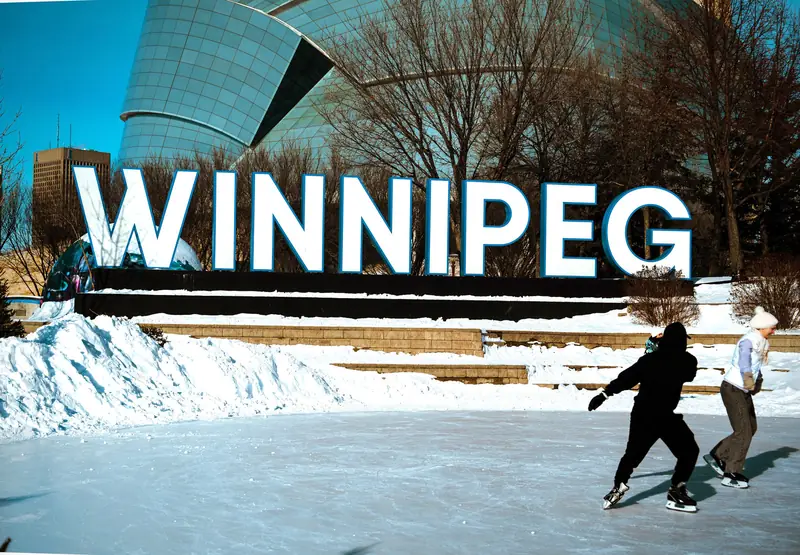 People skating past a city sign at an outdoor rink in winter